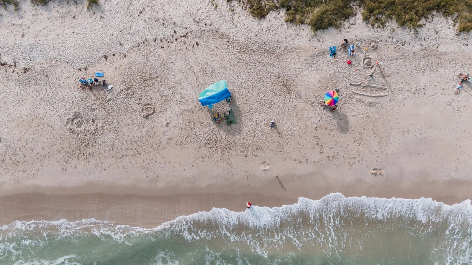 Aerial view of the sand, waves and beach umbrellas at Fort Pierce beach